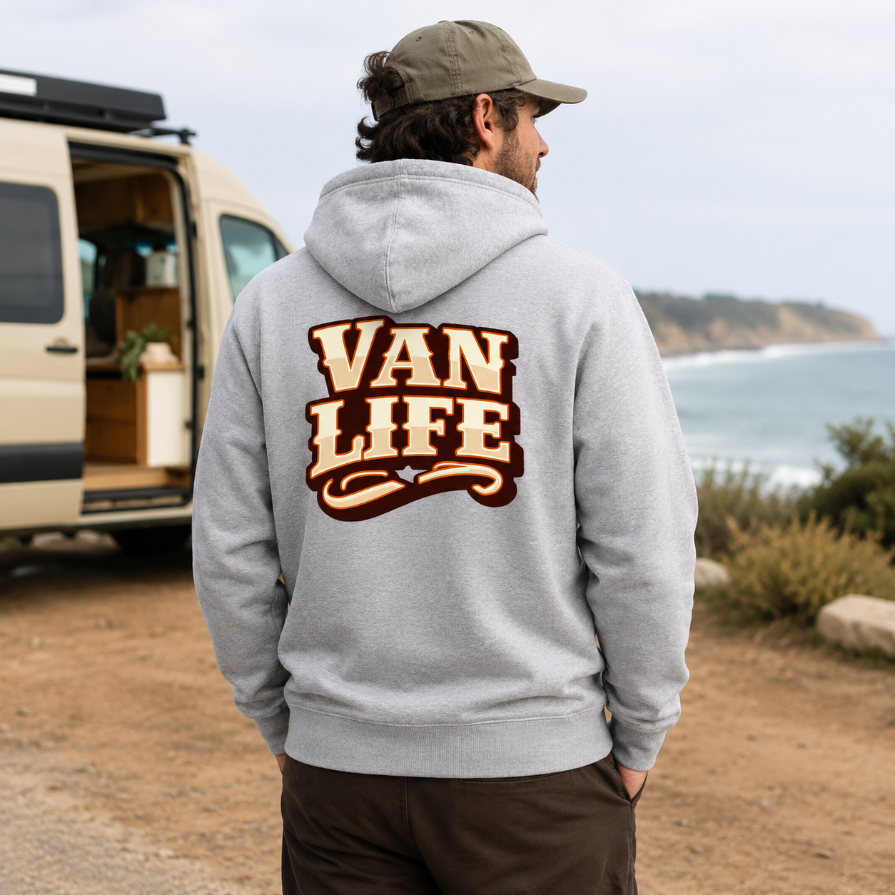Person wearing a hoodie with 'Van Life' text, standing near a van by a body of water.